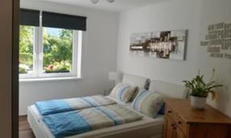 A cozy bedroom with a double bed and colorful pillows. In front of the window, there is a beautiful view of greenery.