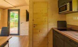 A bright wooden apartment with a modern kitchen. The image shows the access to the terrace and a dining area.