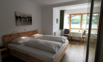 A bright room with a double bed and large windows that offer a view of the landscape. The space is modernly decorated and invites relaxation.