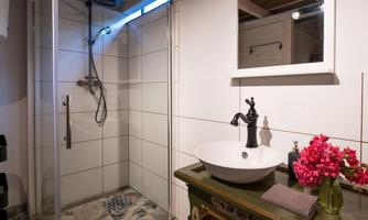 A modern bathroom with a shower and an elegant sink. Fresh flowers and decorative elements add coziness to the space.