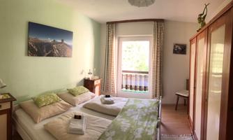A cozy bedroom with two beds and fresh, bright colors. The window lets in plenty of light and offers a view outside.