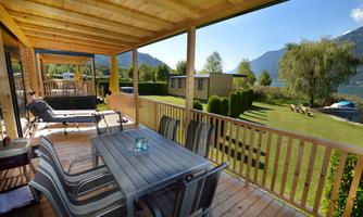 A cozy terrace area with a table and chairs, surrounded by a beautiful landscape. In the background, trees and mountains can be seen.