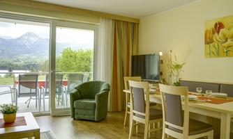 A bright living kitchen with a view of the mountains and the balcony. The room is modern and cozily furnished.