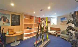 A cozy room with skiing equipment and a seating area. Pictures are hanging on the wall and a price list is visible.