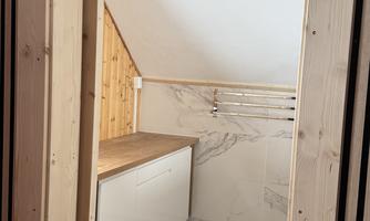 A simple, modern kitchen with wooden shelves and a bright, open space. The floor is laid with laminate and the walls have a light color scheme.