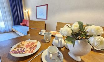 A beautifully set table with dishes and a vase full of flowers. In the background, a cozy seating area can be seen.