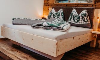 A modern bedroom with a large bed and traditional pillows. The warm wood tones create a cozy atmosphere.