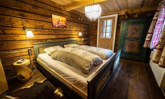 A cozy bedroom in a rustic style with wood paneling. There is a large bed, nightstands, and a decorative lamp.