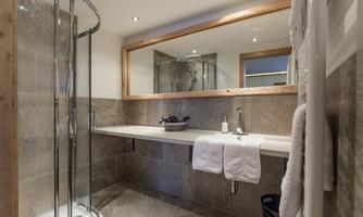 A modern bathroom with a shower, a large mirror, and an elegant sink. The walls are painted in neutral tones, creating a pleasant atmosphere.