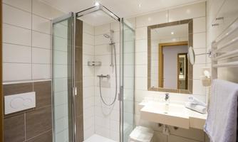 A modern bathroom with a walk-in shower and bright tiles. The mirror and sink are designed in a minimalist and elegant style.