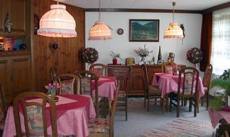 A cozy dining area with round tables and pink tablecloths. The walls are paneled with wood, and decorative lamps hang from the ceiling.