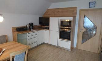 A modern kitchen with wooden and white elements. The space is bright and cozy, with a table and chairs for dining.