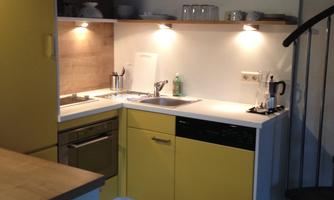 A modern kitchen with yellow cabinets and bright countertops. The lighting creates an inviting atmosphere.