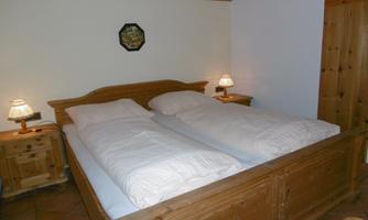 A cozy bedroom with a large wooden bed and two nightstands. The soft lighting creates a relaxed atmosphere.