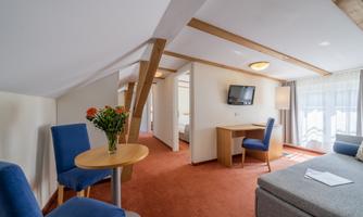 A cozy room with a sofa, a table, and chairs. Large windows provide plenty of light and an inviting atmosphere.