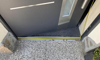 A front door with a smooth floor and a yellow measuring line. The entrance area is clean and modernly designed.