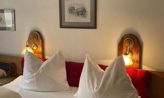 A cozy bedroom with a double bed and large, pointed pillows. A picture hangs on the wall, and there are elegant night lights.