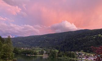 A picturesque lake surrounded by gentle hills, under a colorful sky at sunset. The landscape radiates a calm and peaceful atmosphere.