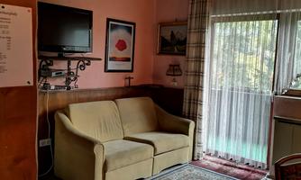 A cozy living space with a beige sofa and a carpet. Large windows provide plenty of natural light.
