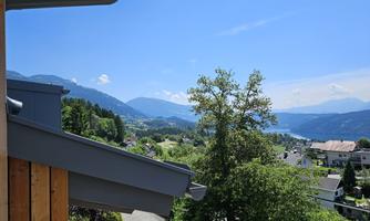 A picturesque view of the mountains, the lake, and the green valley. The sky is clear and radiant blue.