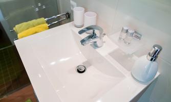 A modern sink with a shiny faucet. Next to the sink are towels and various bathroom items.