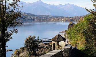 A peaceful landscape by the lake with mountains in the background. The water reflects the colors of the surroundings.