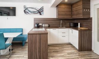Modern kitchen with wooden furniture and white fronts. A cozy seating area with a blue bench completes the room.