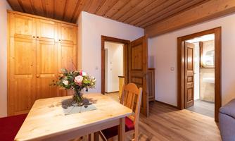 A cozy room with wooden furniture and a table. A vase with flowers is on the table, and there is a pleasant atmosphere.