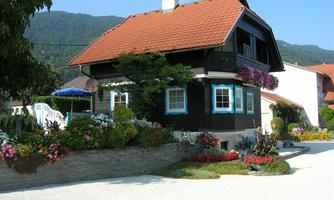 A charming wooden house with a red roof and colorful flowers. The garden is well-maintained and invites you to linger.