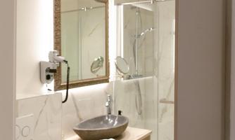 A modern bathroom with an elegant shower and a mirror. The wooden dresser and the sanitary facilities are stylishly arranged.