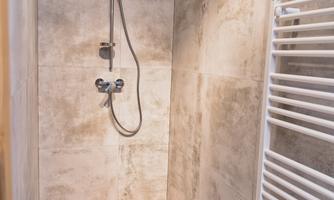 A modern shower with grey walls and a minimalist design. There is a towel warmer on the wall.