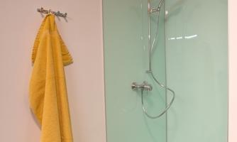 A modern shower with glass walls and a yellow towel. The room has a bright and clean atmosphere.