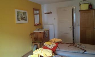 A cozy room with yellow walls and a wooden wardrobe. Folded towels in various colors are placed on the bed.