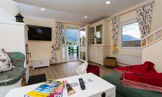 A cozy living room with a green couch and a red armchair. Large windows offer a beautiful view of the mountains.