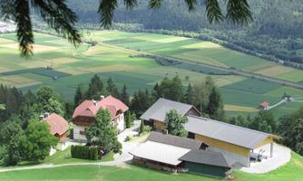 An idyllic landscape with several farmhouses and green meadows. In the background, fields and forests stretch out.