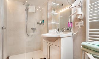 A modern bathroom with a shower and a sink. Bright walls and a clean, stylish decor create an inviting atmosphere.
