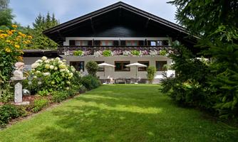 A beautiful house with a balcony and a well-maintained garden. The surroundings are green with many flowers and plants.