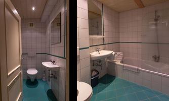 A modern bathroom with white tiles and blue accents. It features a bathtub, a sink, and a toilet.