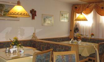 A cozy restaurant with wooden furniture and colorful cushions. Soft light from the lamps creates an inviting atmosphere.