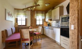 A cozy kitchen with wooden decor and a dining area. The modern equipment includes a stove and a refrigerator.