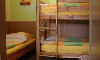 A simple room with a bunk bed and a single bed. The walls are painted in a light green color and adorned with a decorative picture.