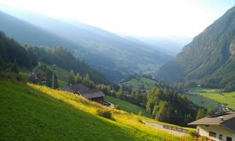 A picturesque mountain landscape with gentle hills and green meadows. In the background, the rugged mountains and a clear sky can be seen.