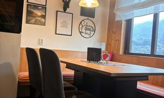 A cozy dining area with a wooden table and elegant chairs. Pictures and decorations hang on the walls, creating a warm ambiance.