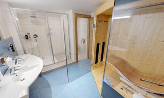 A modern bathroom with showers and a sauna. The walls are bright, and there are elegant sinks.