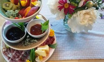 A decorative plate with various delicacies such as sausage, cheese, and fruits. Next to it stands a vase with colorful flowers.