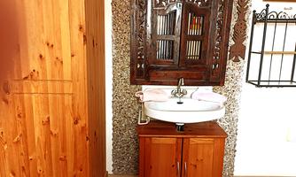 A bathroom with a white sink on a wooden furniture. The walls are designed with beautiful decorative elements and wood paneling.