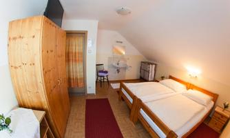 A cozy bedroom with two single beds and wooden furniture. The room has a warm, inviting atmosphere.