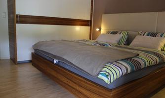 A modern bedroom with a large double bed and colorful bedspreads. The wooden details and the pleasant lighting create a cozy atmosphere.