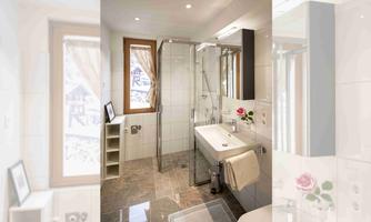 A modern bathroom with a glass shower and bright tiles. Large windows provide plenty of natural light and a friendly atmosphere.