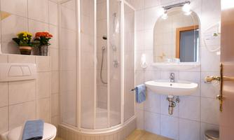 A bright bathroom with a shower and a sink. Flowers and towels give the room an inviting atmosphere.